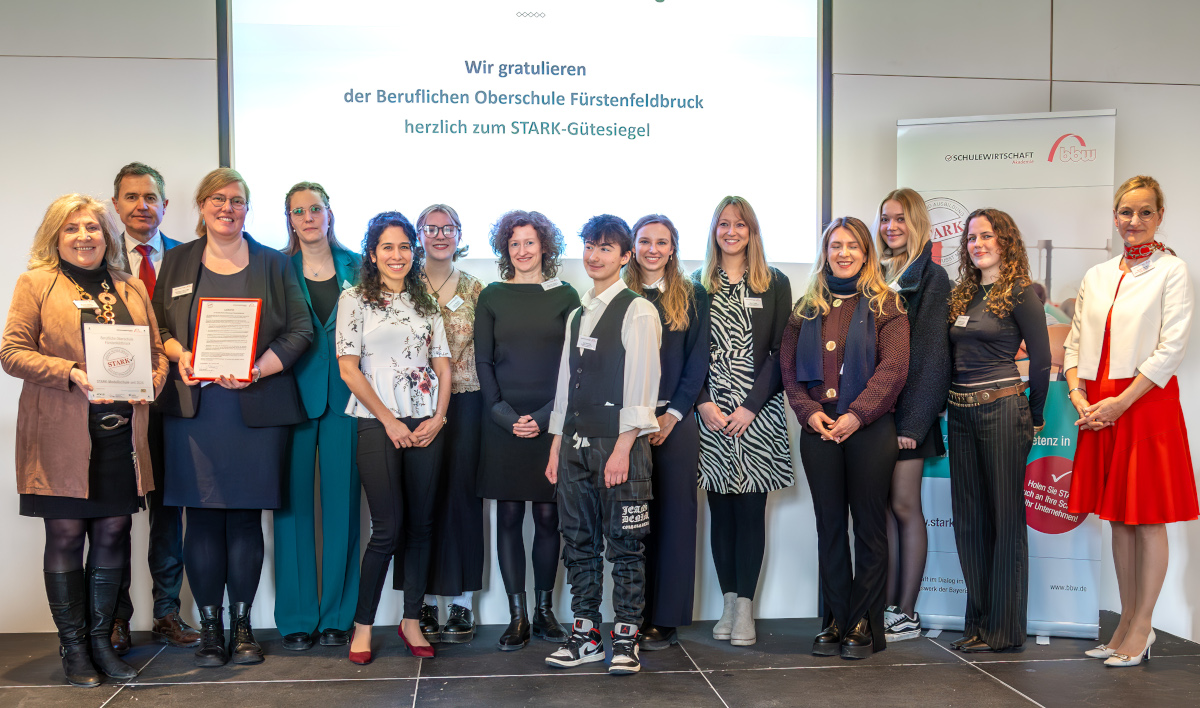 Personengruppe auf Bühne nach Verleihung des STARK-Gütesiegels an die Berufliche Oberschule Fürstenfeldbruck, mit Schulleitung, Kollegium, Schülerschaft sowie Robert Geiger (StMUK) und Sandra Stenger (bbw-Gruppe).