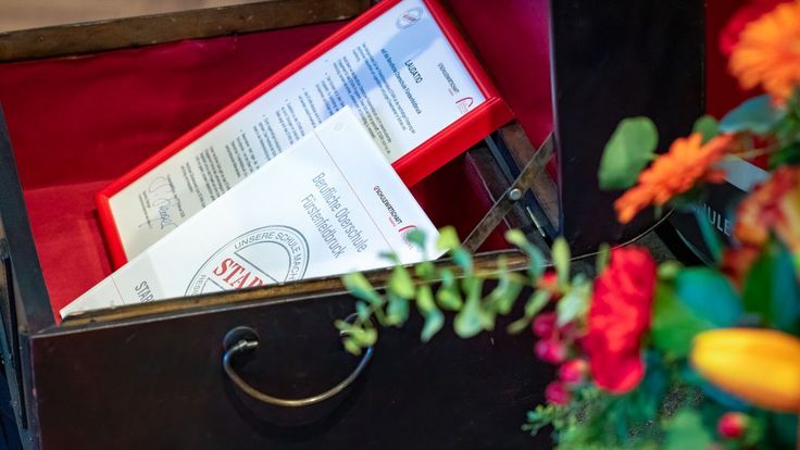 Truhe mit Gütesiegel und gerahmter Laudatio für die Berufliche Oberschule Fürstenfeldbruck
