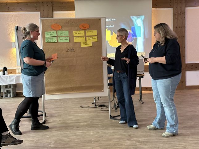 Drei Teilnehmerinnen diskutieren vor der Pinnwand